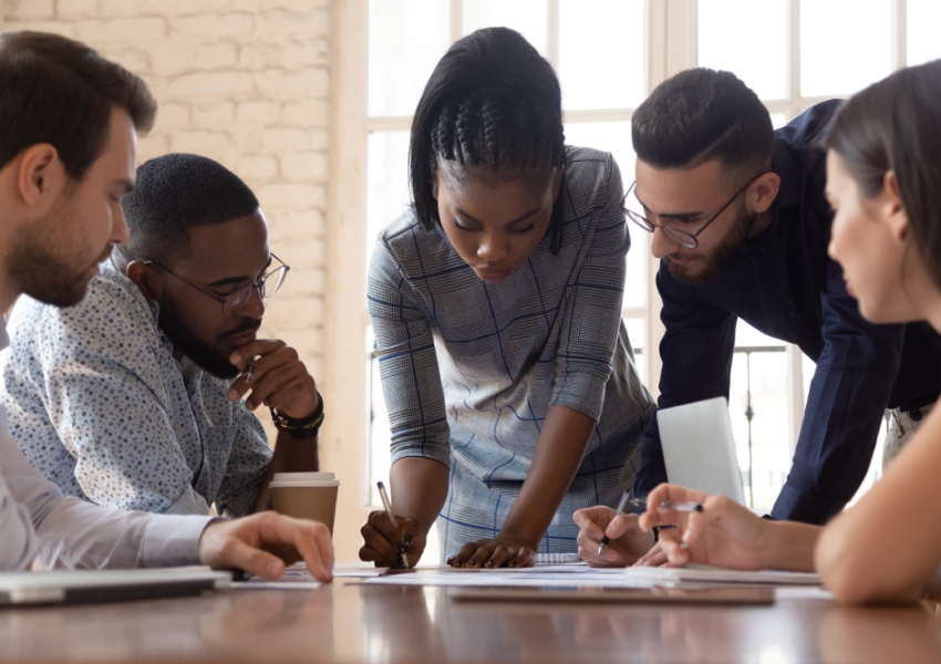 5 people having a meeting at work and taking notes
