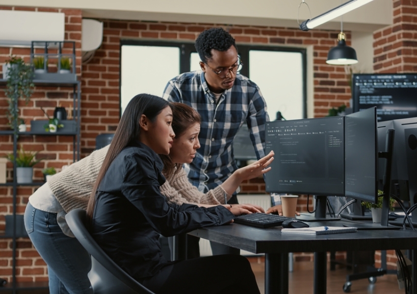 3 people at the office watching two computer screens